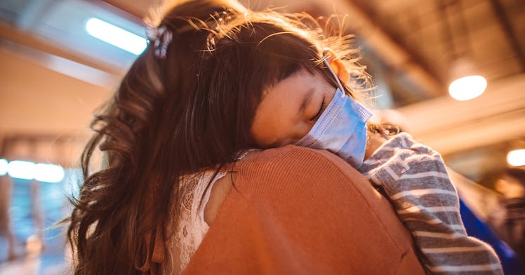 a child with a mask hugging an adult