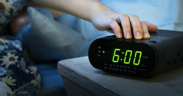 A hand reaches out toward a clock