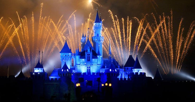A view at a Disney Park with yellow fireworks and blue lights