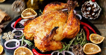 A Thanksgiving turkey next to slices of lemon, onion and red peppers on a black plate