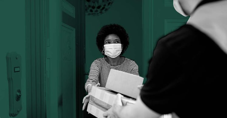 A woman wearing a face mask receiving packages at her front door