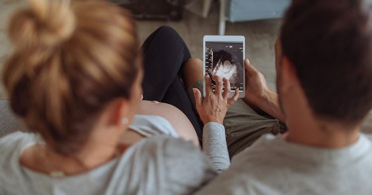 A woman and a man looking at the image of a baby scan to find out the sex of their baby