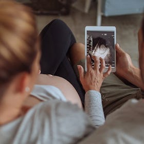 A woman and a man looking at the image of a baby scan to find out the sex of their baby