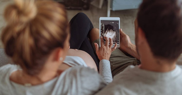 A woman and a man looking at the image of a baby scan to find out the sex of their baby
