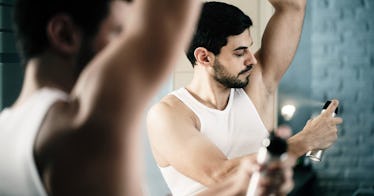 A man applying deodorant in a bathroom.