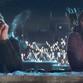 Kate and Clint standing on a roof during winter, Hawkeye is looking through binoculars