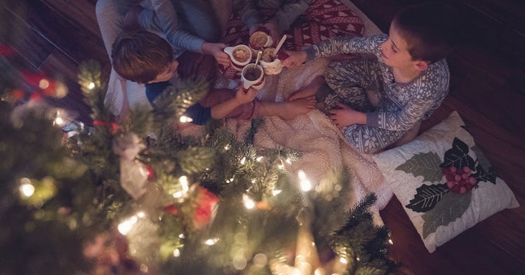 A family in their pajamas sitting near their Christmas tree.