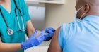 一名男子从戴着手套的医疗专业人员那里接受HPV疫苗。