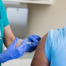 A man receives the HPV vaccine from a healthcare professional who is wearing gloves.