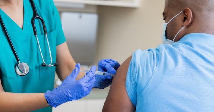 A man receives the HPV vaccine from a healthcare professional who is wearing gloves.