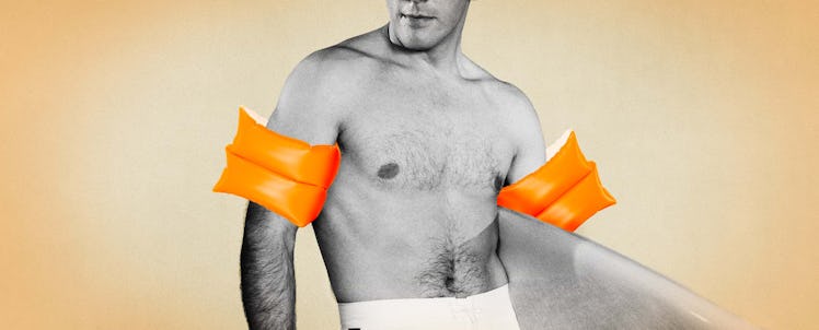 A man wearing orange arm floaties while holding a surf board. 