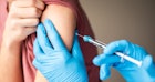一个戴着乳胶手套的医疗专业人员给一个十几岁的男孩注射脑膜炎疫苗的特写镜头。