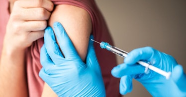 Close up of a medical professional wearing latex gloves giving a tween boy a meningitis vaccine.