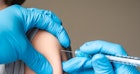 一位戴着蓝色手套的医务人员正在给孩子注射水痘疫苗。
