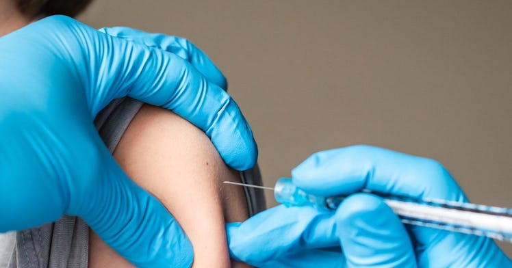 A medical professional wearing blue gloves gives a child the chickenpox vaccine.