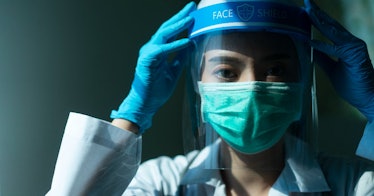 A doctor wear a mask, face shield, and gloves.
