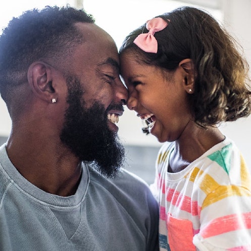 A father and daughter laugh with their foreheads touching.