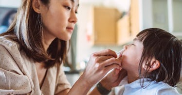 A woman administers an at-home COVID test to her child