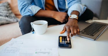 an unrecognizable person calculates fiances with a cup of tea