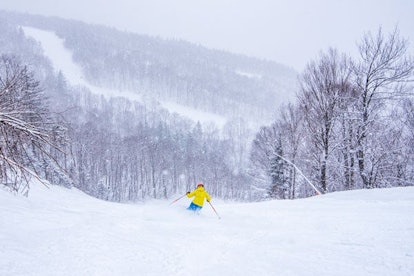 A man in a yellow jacket skiing at Sunday River ski resort