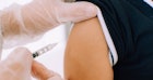 一位戴着手套的医务人员给一个小男孩注射MMR疫苗。
