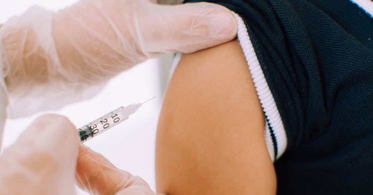 A medical professional wearing gloves gives a young boy the MMR vaccine.