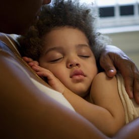 A small girl sleeping on their mother's chest