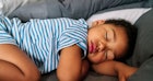 一个穿着条纹连体衣的孩子睡着了。