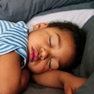 A child in a striped onesie sleeps.