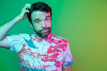 Image of comedian Chris Garcia in a tie-dye button up shirt with green background.