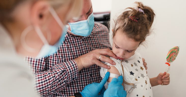 A dad holds his daughter, under age 5, as she receives the COVID-19 vaccine.
