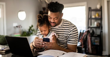dad holding daughter looking phone computer