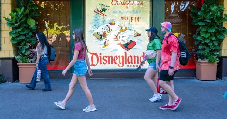 a couple of people with and without masks walk around in Disneyland