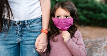一个戴着口罩的小女孩牵着妈妈的手。