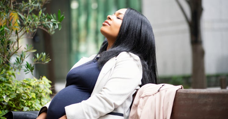 A pregnant person reclines on a bench.