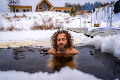 在沙谷度假村，一名男子在被雪包围的热水浴缸里