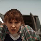 Eleven is being held by two suited men in a Stranger Things screenshot