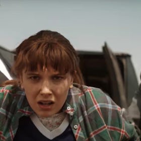 Eleven is being held by two suited men in a Stranger Things screenshot