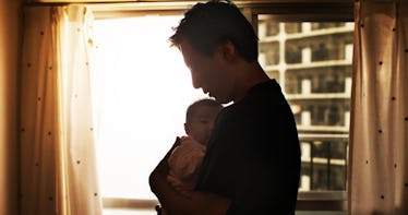 Dad holding young baby while light enters through window