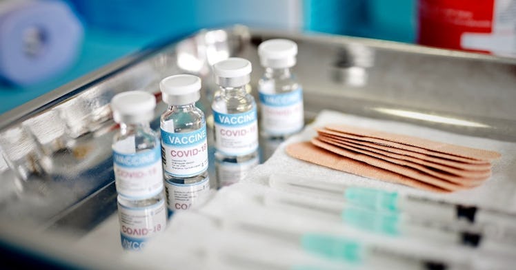 Four vaccine vials on a tray with syringes.