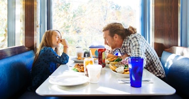 father and daughter laughing and talking at diner booth