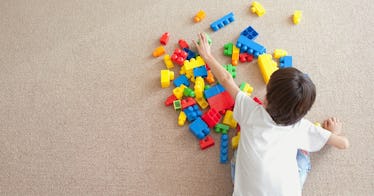 A child plays with colorful blocks on the floor.