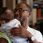 A dad burps his baby against his shoulder.