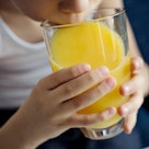 Close up of a child drinking orange juice.