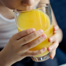 Close up of a child drinking orange juice.