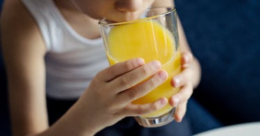 Close up of a child drinking orange juice.