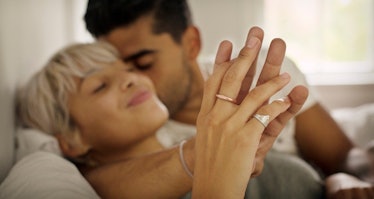 Man and woman smiling and touching hands in bed