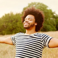 Happy man standing in sunlit field with arms outstretched
