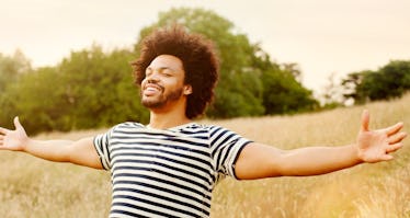 Happy man standing in sunlit field with arms outstretched