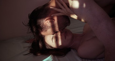Couple touching foreheads in bed with light casting on them